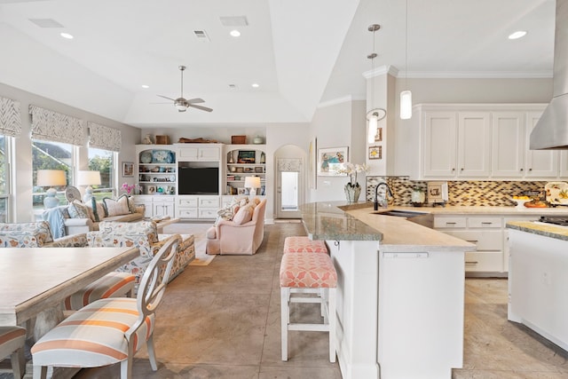 kitchen featuring kitchen peninsula, sink, hanging light fixtures, and white cabinets