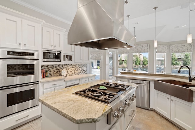 kitchen with appliances with stainless steel finishes, island range hood, white cabinetry, decorative backsplash, and a center island