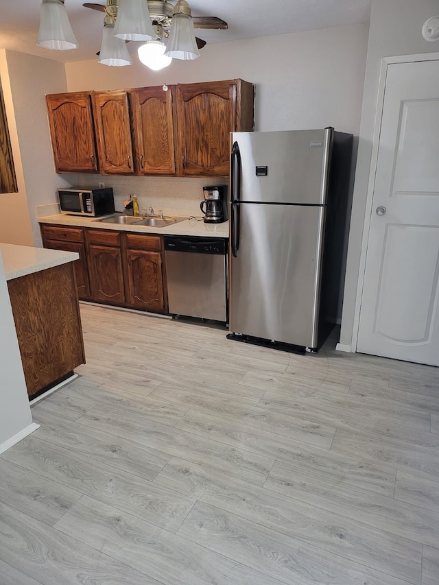 kitchen with stainless steel appliances, ceiling fan, light hardwood / wood-style floors, and sink