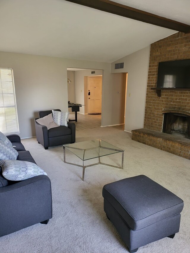 living room with vaulted ceiling with beams, light colored carpet, and a brick fireplace