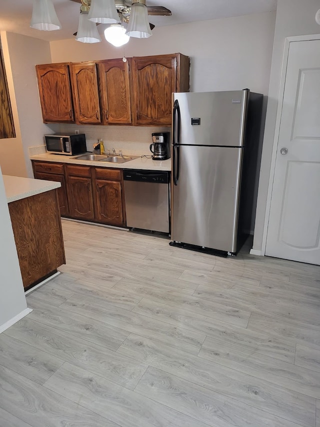 kitchen featuring ceiling fan, sink, stainless steel appliances, and light hardwood / wood-style floors