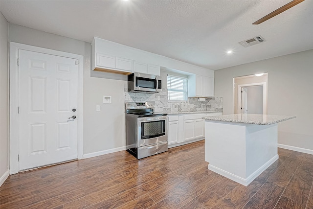 kitchen featuring stainless steel appliances, a kitchen island, sink, dark hardwood / wood-style floors, and white cabinetry