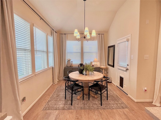 dining room featuring a healthy amount of sunlight, light hardwood / wood-style floors, lofted ceiling, and a notable chandelier