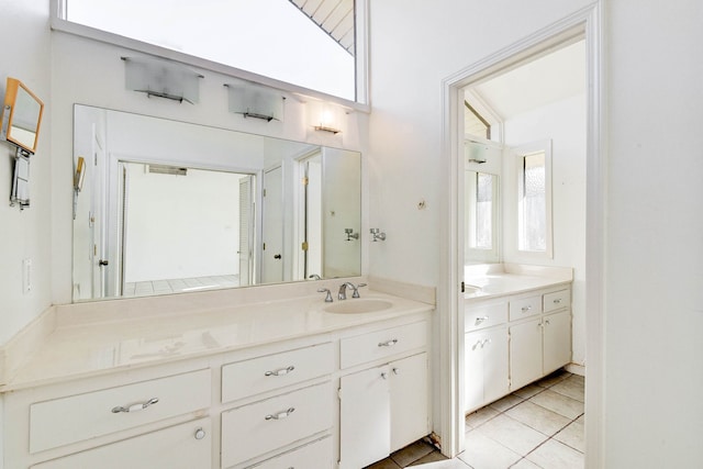 bathroom with tile patterned flooring, vanity, and a healthy amount of sunlight