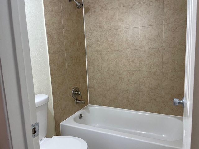 bathroom with tiled shower / bath combo and toilet