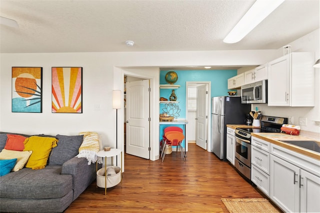 kitchen featuring dark hardwood / wood-style floors, white cabinetry, a textured ceiling, and appliances with stainless steel finishes