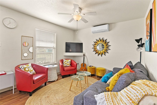 living room featuring a wall unit AC, ceiling fan, wood-type flooring, and a textured ceiling