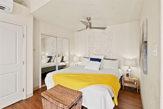 bedroom with ceiling fan, dark hardwood / wood-style flooring, an AC wall unit, and a closet