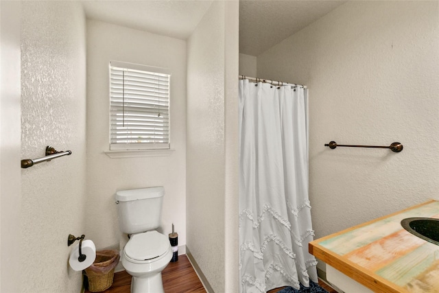 bathroom with hardwood / wood-style floors, a shower with shower curtain, and toilet