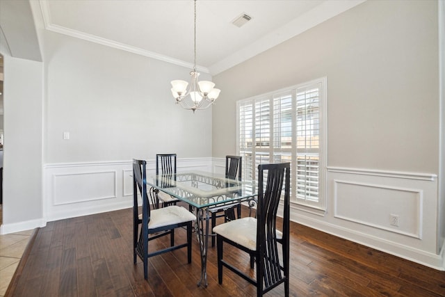 dining space featuring an inviting chandelier, ornamental molding, and dark hardwood / wood-style floors