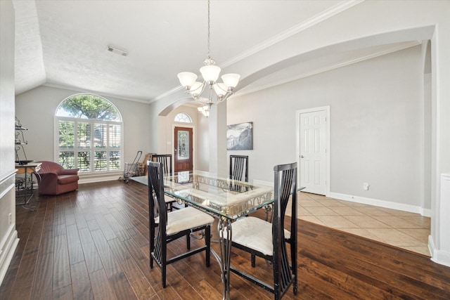 dining room with wood-type flooring, vaulted ceiling, ornamental molding, and a chandelier