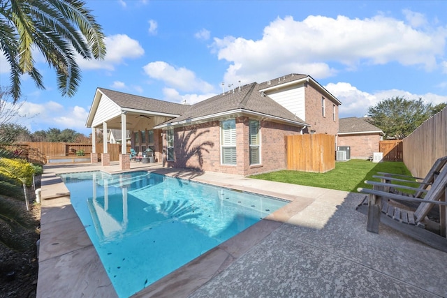 view of pool featuring ceiling fan, a yard, central AC unit, and a patio area