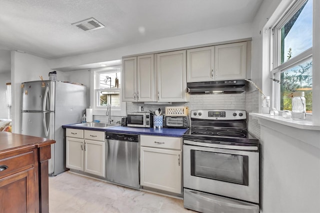 kitchen with decorative backsplash, a healthy amount of sunlight, sink, and appliances with stainless steel finishes