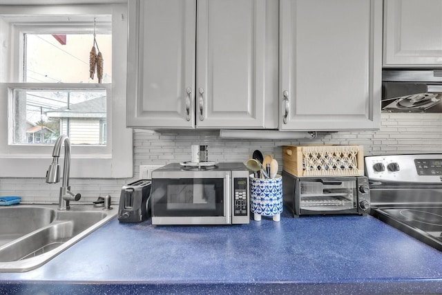 kitchen featuring backsplash, white cabinets, sink, appliances with stainless steel finishes, and extractor fan