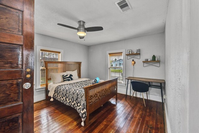 bedroom featuring ceiling fan, dark hardwood / wood-style flooring, and a textured ceiling