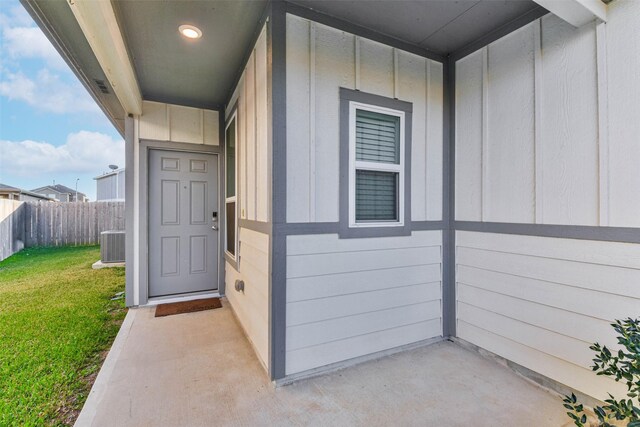 entrance to property featuring a yard and central air condition unit