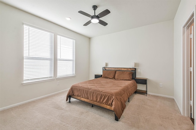 bedroom with a ceiling fan, light colored carpet, and baseboards