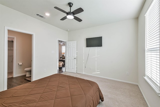 bedroom featuring ensuite bath, baseboards, visible vents, and dark carpet