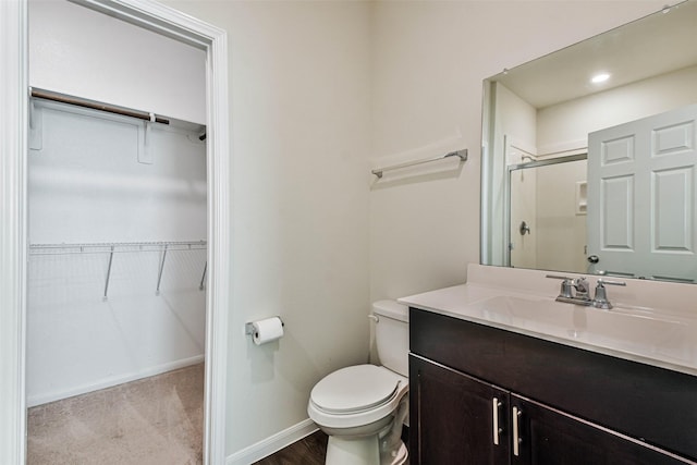 full bath with toilet, vanity, baseboards, a spacious closet, and a shower stall