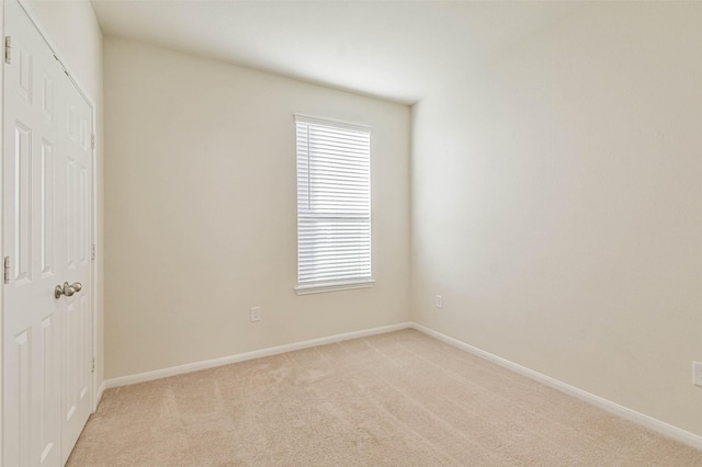 unfurnished bedroom featuring a closet, light carpet, and baseboards