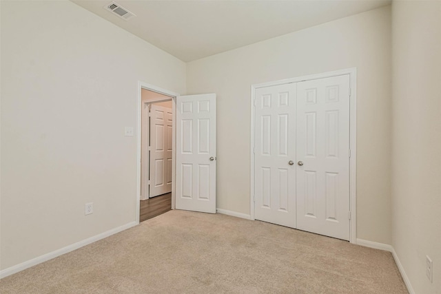 unfurnished bedroom with baseboards, visible vents, and light colored carpet