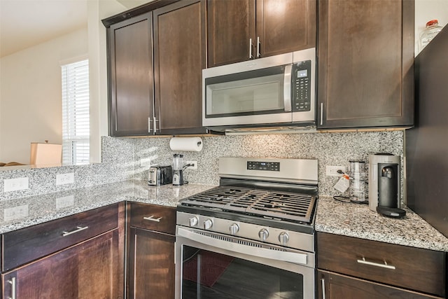 kitchen featuring stainless steel appliances, light stone counters, backsplash, and dark brown cabinets