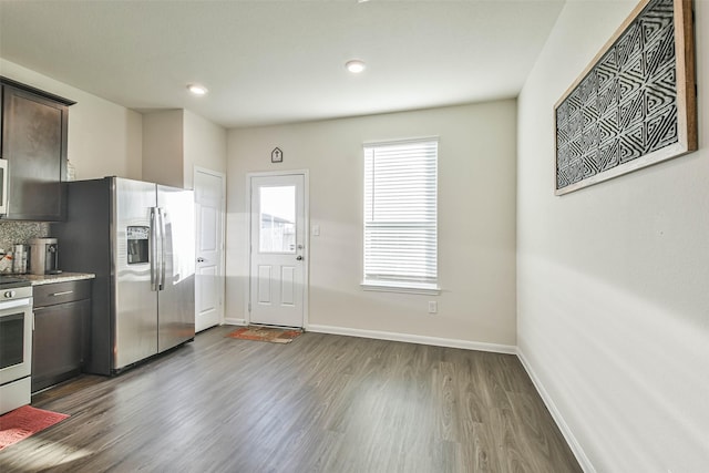 kitchen featuring stainless steel appliances, wood finished floors, baseboards, dark brown cabinets, and light countertops