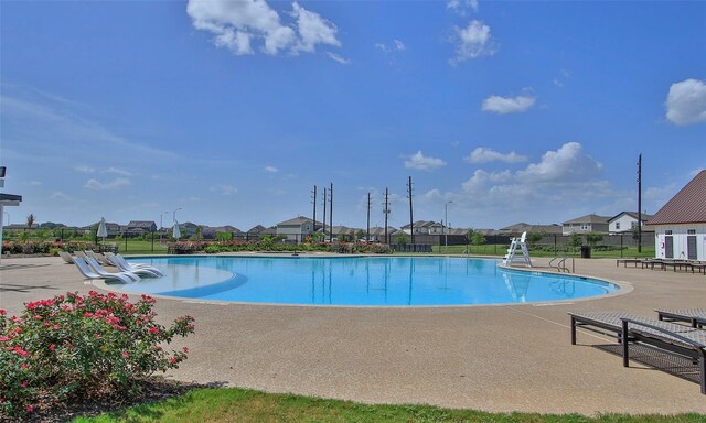 community pool featuring a residential view, fence, and a patio