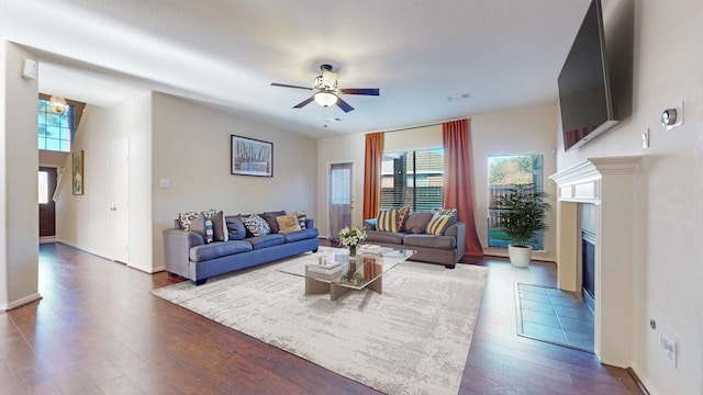 living area with dark wood-style flooring, a tiled fireplace, visible vents, and a healthy amount of sunlight