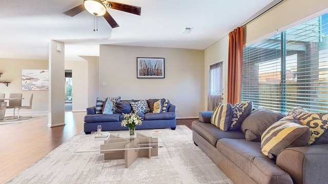 living room featuring visible vents, ceiling fan, baseboards, and wood finished floors