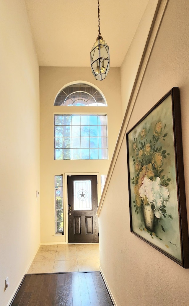 foyer entrance featuring a towering ceiling and light wood-type flooring