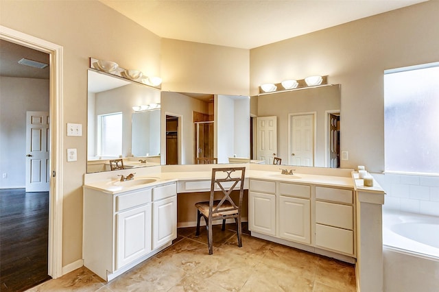 bathroom with a garden tub, visible vents, two vanities, and a sink