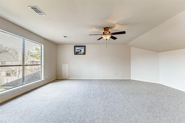 empty room with carpet floors, visible vents, ceiling fan, and a textured ceiling