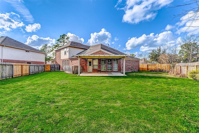 rear view of house with brick siding, a patio, and a fenced backyard