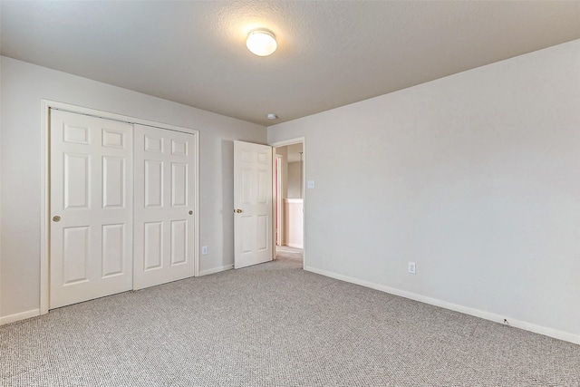 unfurnished bedroom featuring carpet floors, a textured ceiling, baseboards, and a closet