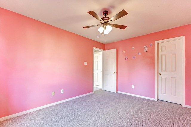 carpeted spare room with ceiling fan and baseboards