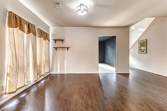 spare room featuring dark wood-style floors and visible vents