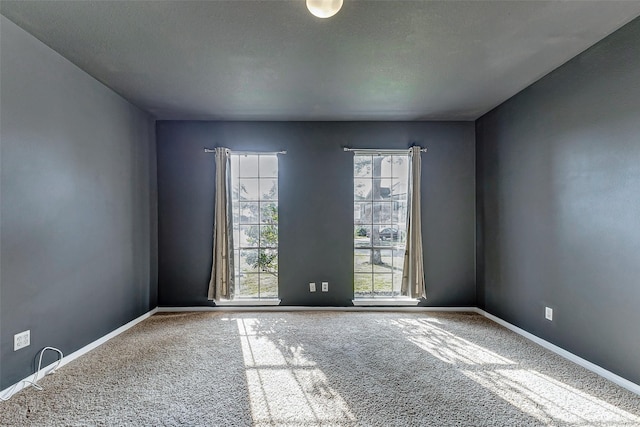 spare room featuring carpet, baseboards, and a textured ceiling