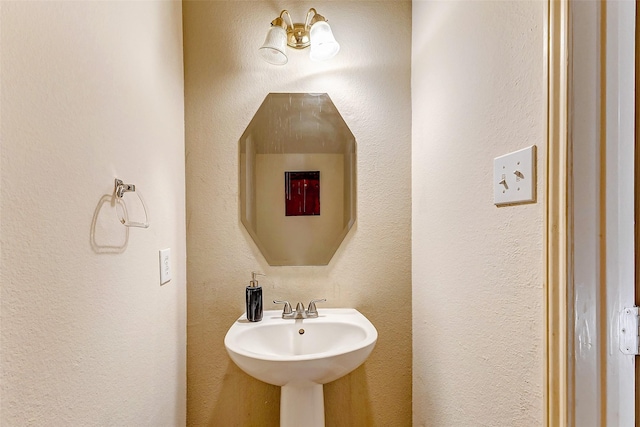 bathroom featuring a textured wall and a sink