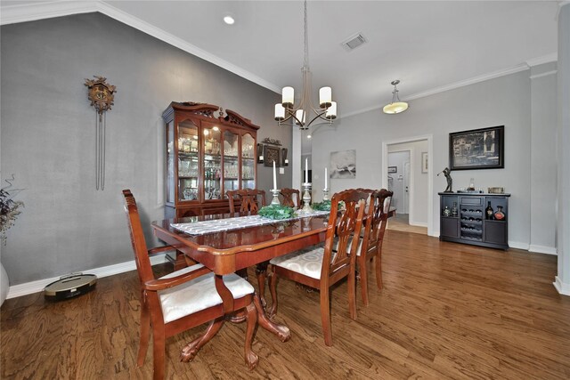 dining area featuring crown molding, hardwood / wood-style floors, lofted ceiling, and a notable chandelier