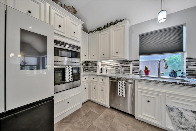 kitchen with light stone countertops, stainless steel appliances, sink, white cabinets, and hanging light fixtures