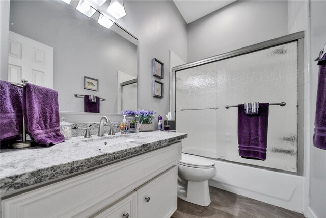 full bathroom featuring shower / bath combination with glass door, tile patterned flooring, vanity, and toilet