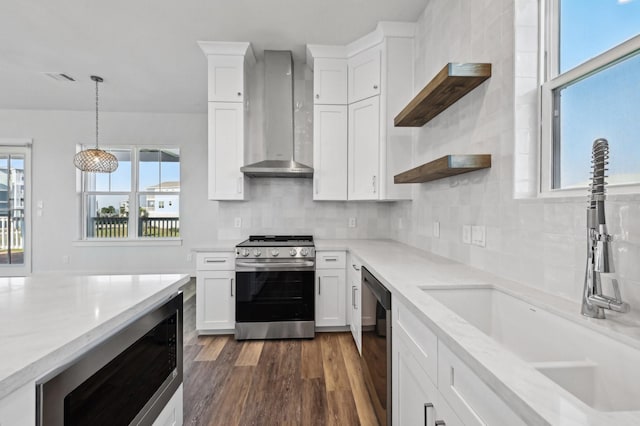 kitchen with white cabinetry, sink, wall chimney exhaust hood, light stone counters, and stainless steel stove