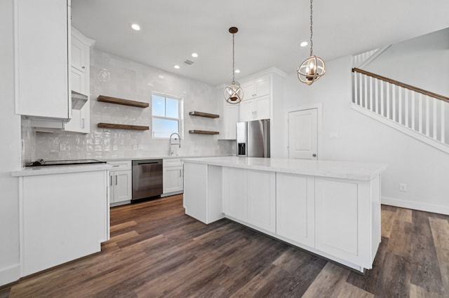 kitchen with a center island, backsplash, hanging light fixtures, white cabinetry, and stainless steel appliances