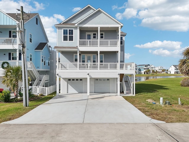 coastal home featuring a garage, a water view, and a front lawn