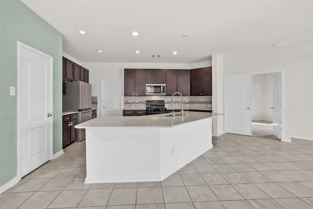 kitchen with decorative backsplash, gas stove, an island with sink, and sink