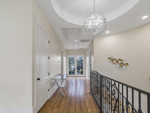 corridor featuring hardwood / wood-style floors, french doors, and a notable chandelier