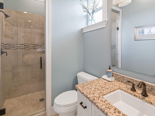 bathroom featuring vanity, toilet, and a shower with shower door