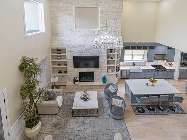 living room featuring an inviting chandelier, light hardwood / wood-style flooring, plenty of natural light, and sink