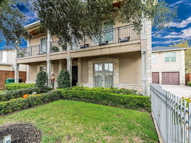 view of front of home with a front yard, a balcony, and a garage